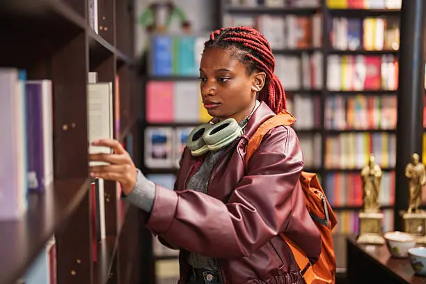 Young woman browsing books in a bookstore Framework to Narrow Your Thesis Topic